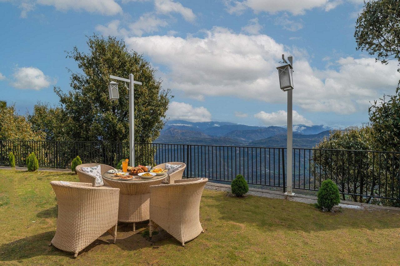 Breakfast on a round cane table on the lawn, with the mountains behind