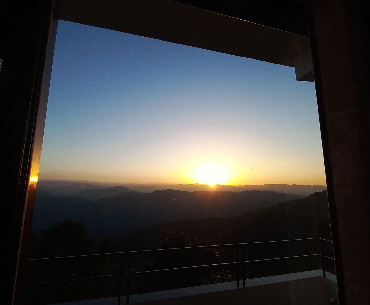 The sun rising over the mountains, framed by the room window