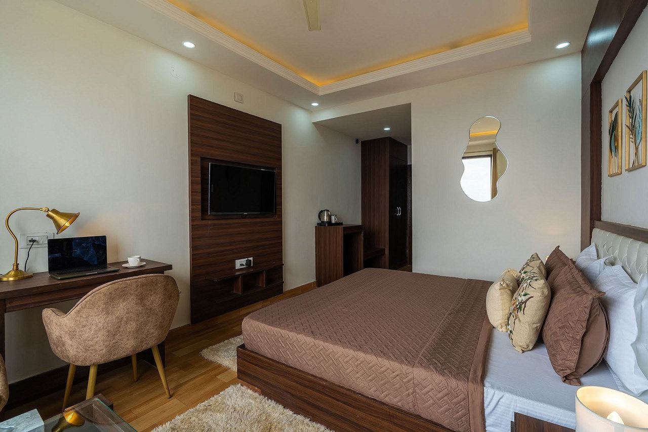 A work desk with a lamp and a laptop beside the bed