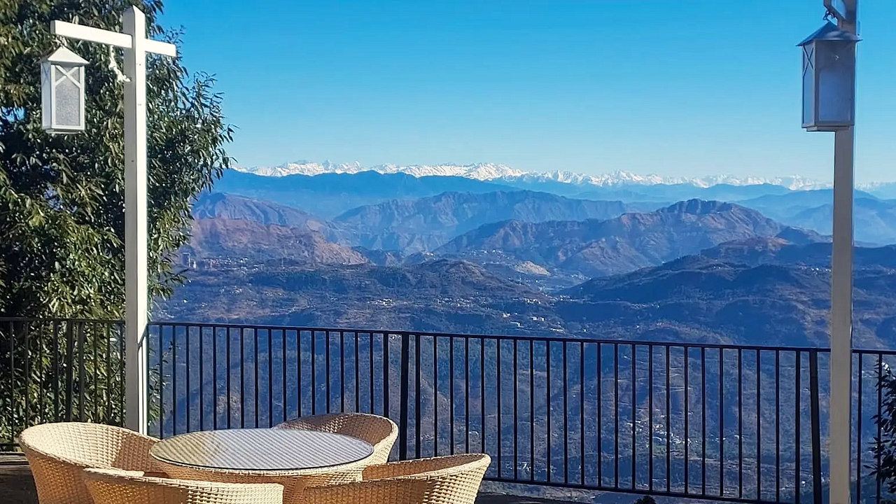 Snow peaks beyond the lantern posts and cane chairs on the terrace