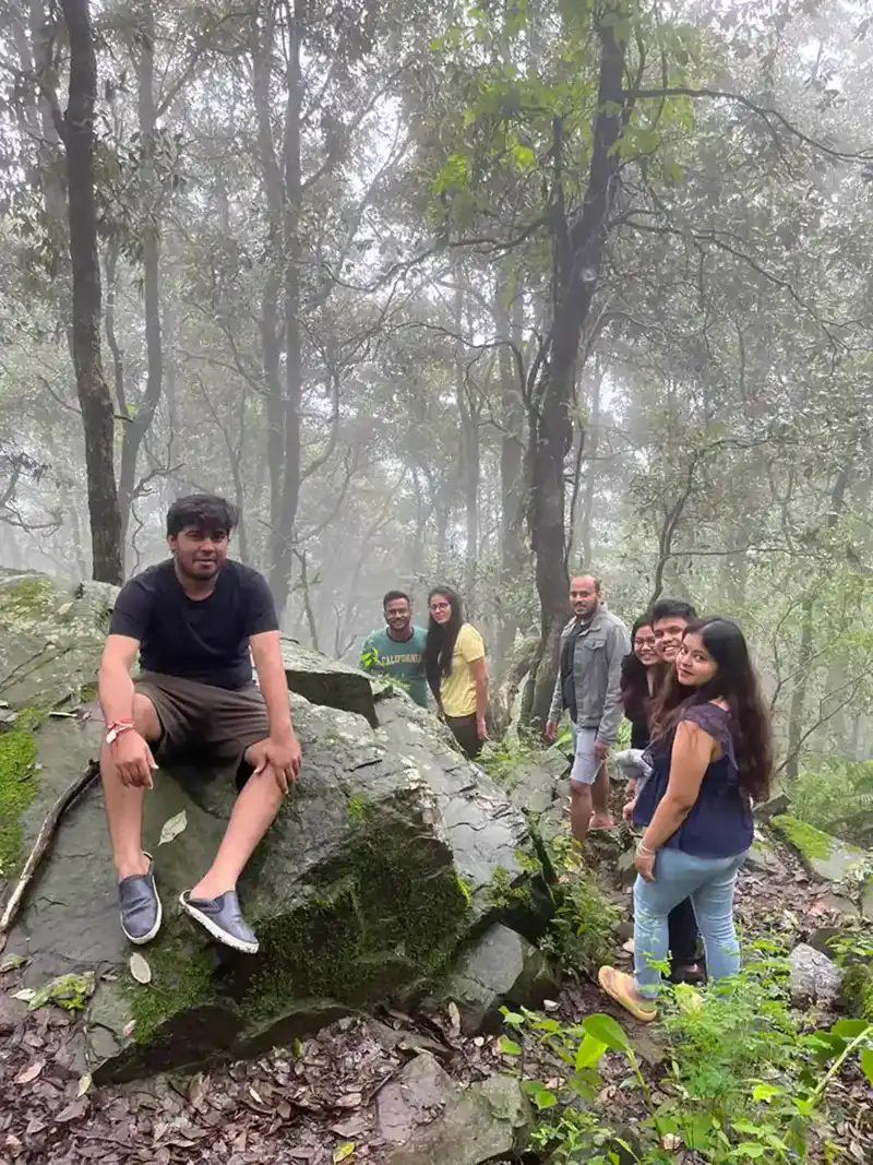 Friends posing on a mossy rock in the misty forest