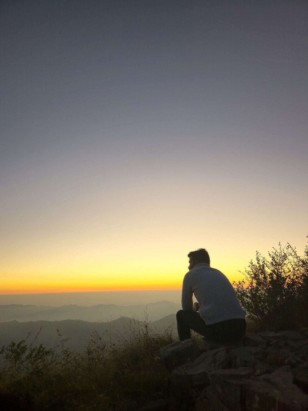 A guest sitting on the ridge, watching the sunset glow over the hills