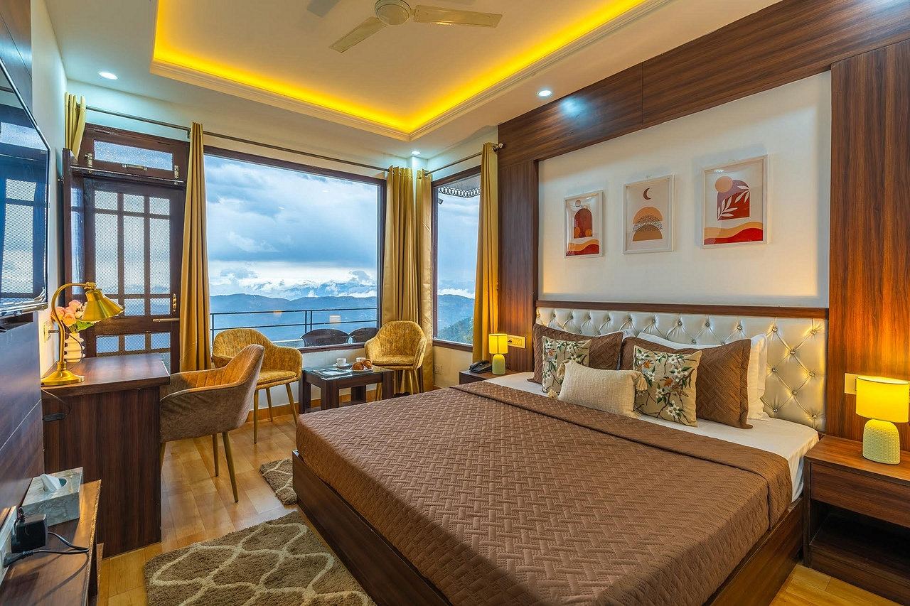 Room with a large window, two armchairs and a brown bedspread